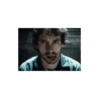 a man with curly hair and a beard is sticking out his tongue