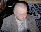 a man in a suit and tie sits in front of a pillow that says hey 300