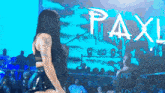a woman dances in front of a sign that says paxl