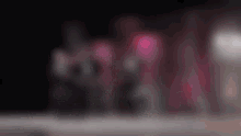a blurry picture of a group of people standing in a dark room with red lights behind them .