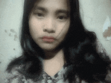 a woman with long black hair looks at the camera with a serious look on her face