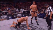 a wrestler is kneeling down in front of a sign that says aew on it