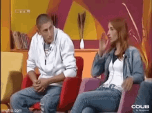 a man and a woman are sitting in chairs on a television show .