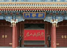 two guards stand in front of a building with chinese writing
