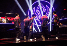 a group of people standing in front of a stage with a purple logo on it