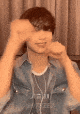 a young man wearing headphones and a denim jacket is making a face
