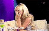 a woman is sitting on a couch covering her face with her hand