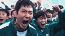 a group of people are screaming and one of them has the number 001 on his jacket
