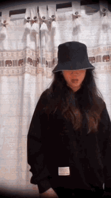 a woman wearing a black bucket hat and a black sweatshirt