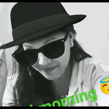 a woman wearing a hat and sunglasses has the word morning written on her shirt