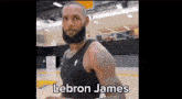a basketball player with a beard is standing on a basketball court in a gym .