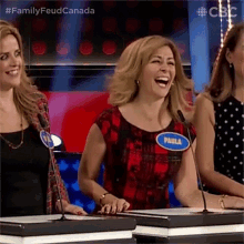 a woman with a name tag that says paula is laughing while playing a game show .