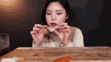a woman is eating a piece of food on a cutting board