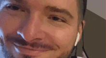 a close up of a man 's face with a beard and ear buds .
