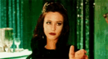 a woman in a black dress giving a thumbs up