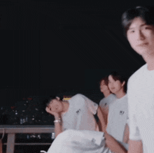 a group of young men wearing white shirts with the letter n on them are standing in a dark room .