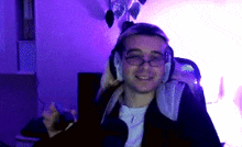 a man wearing glasses and headphones is smiling in front of a purple background