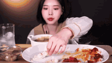 a woman reaches for a piece of food from a plate