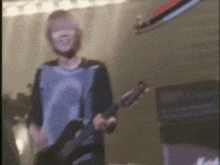 a man is playing a guitar on a stage in a blurry photo .