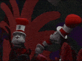 two stuffed animals wearing red hats are standing next to each other in a dark room .