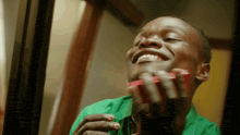 a man in a green shirt smiles while shaving his face