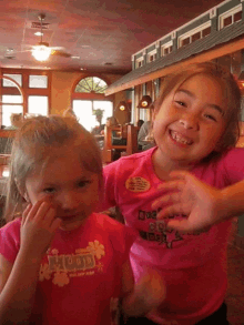 two little girls are posing for a picture and one has a shirt that says hood on it