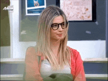 a woman wearing glasses is sitting in front of a sign that says ant2