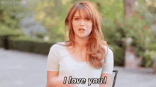 a woman in a white shirt is sitting in a chair and says i love you .