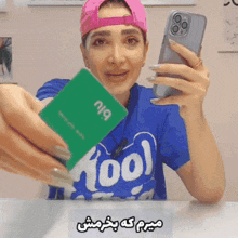 a woman wearing a blue shirt that says fool is holding a phone