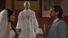 a bride and groom standing in front of a priest