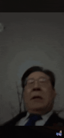 a close up of a man wearing glasses and a tie making a funny face .