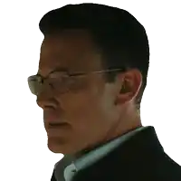 a man wearing glasses and a black jacket looks to his left