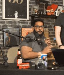 a man with a beard is sitting at a table with a bottle of heineken on it