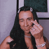 a man with long hair is making a middle finger gesture and smiling .