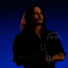 a man with long hair and a mustache is wearing a black shirt