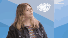 a woman stands in front of a blue wall with the words elite daily on it
