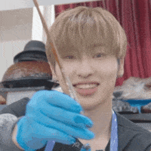 a young man wearing blue gloves is smiling while holding a stick