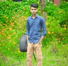 a young man in a plaid shirt holds a backpack