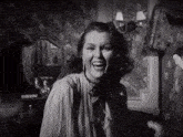 a woman laughs in front of a mirror in a black and white photo
