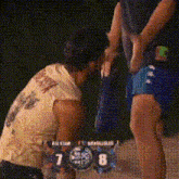 a man is kneeling down in front of a scoreboard that says 7 to 8