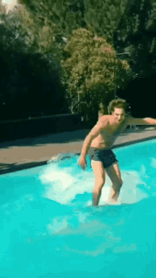a man without a shirt is jumping into a pool