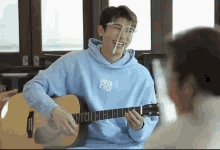 a young man wearing a face shield is playing a guitar .