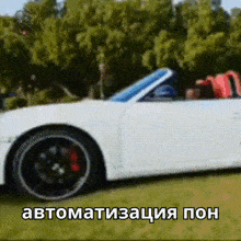 a white sports car is parked in a grassy field with trees in the background and a caption in a foreign language