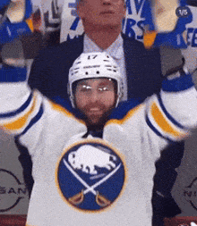a hockey player with his arms in the air wearing a jersey with a buffalo on it