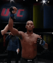 a shirtless fighter in a ufc ring stands in front of a large ufc sign