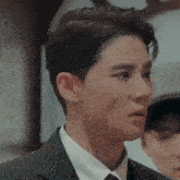 a man in a suit and tie is looking at the camera .