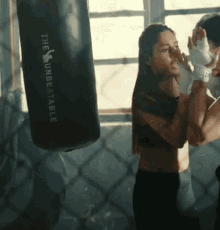 a woman boxing with a punching bag that says the unbeatable on it