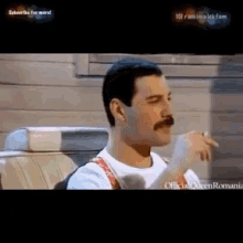 freddie mercury is smoking a cigarette in a car .