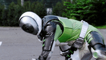 a person wearing a helmet and a green and black suit is crawling on the ground