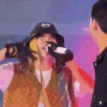 a man is drinking from a bottle while wearing a hat with googly eyes